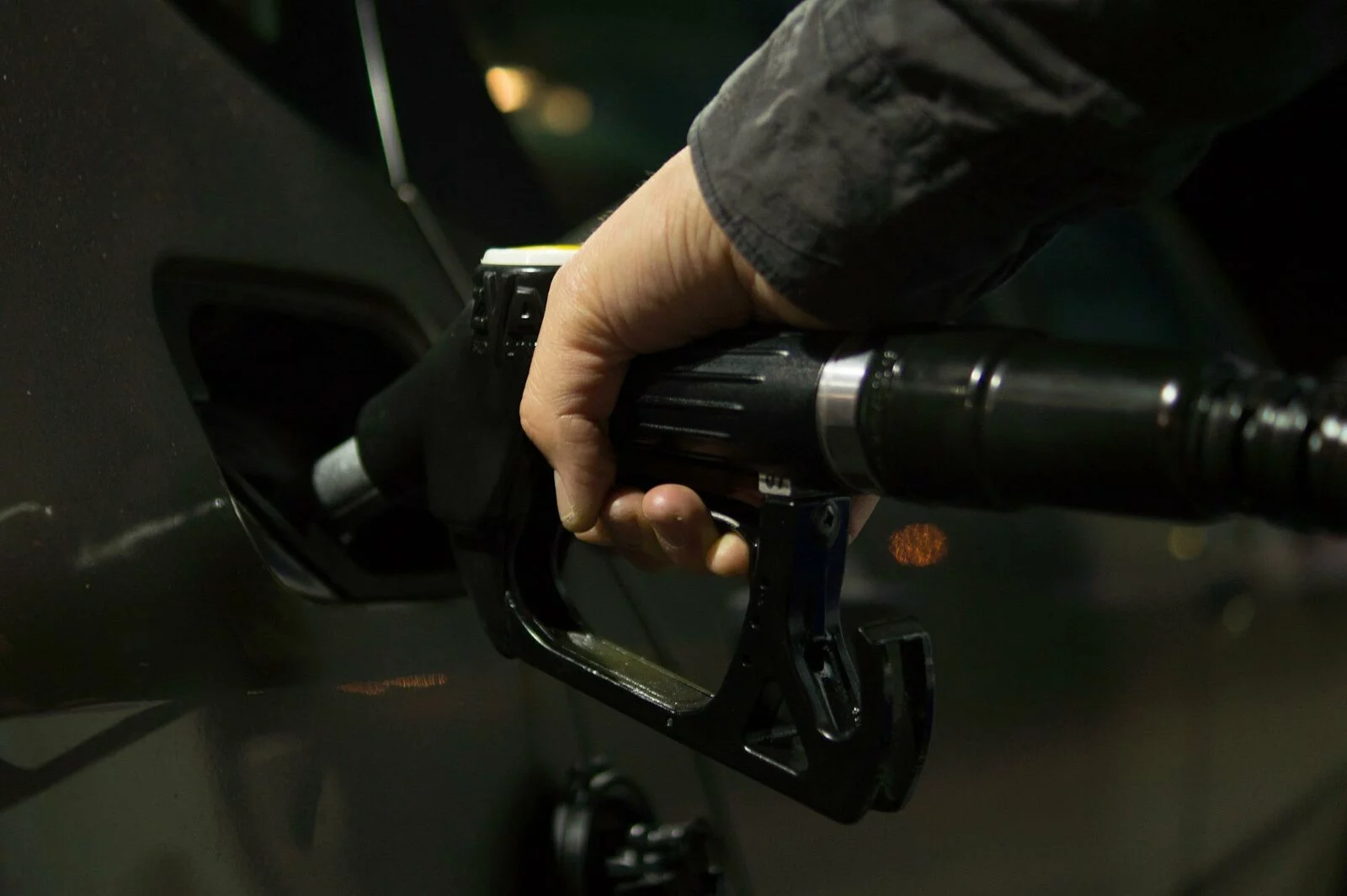 Person holding a gas nozzle and pouring fuel into a car at a Conrad and Bischoff gas station.